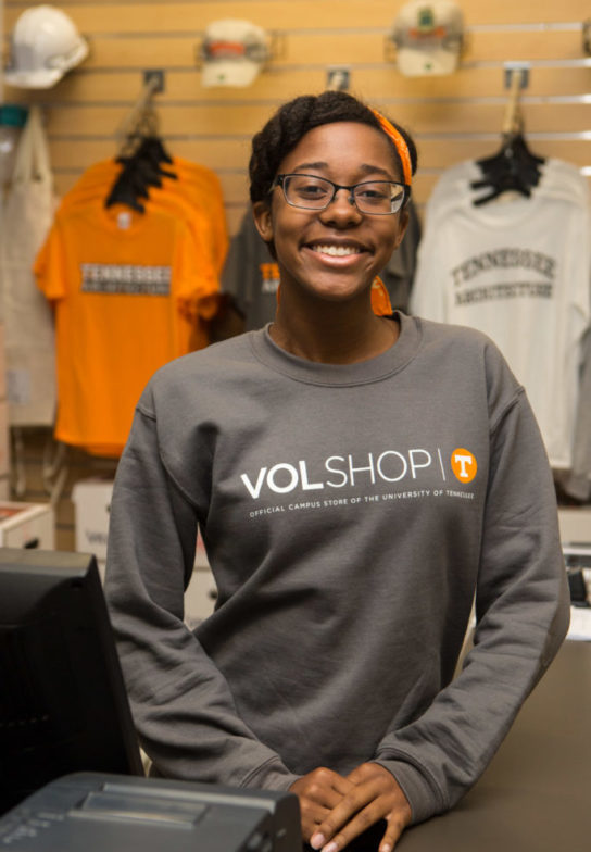 A young woman wearing a VolShop shirt stands in the bookstore.
